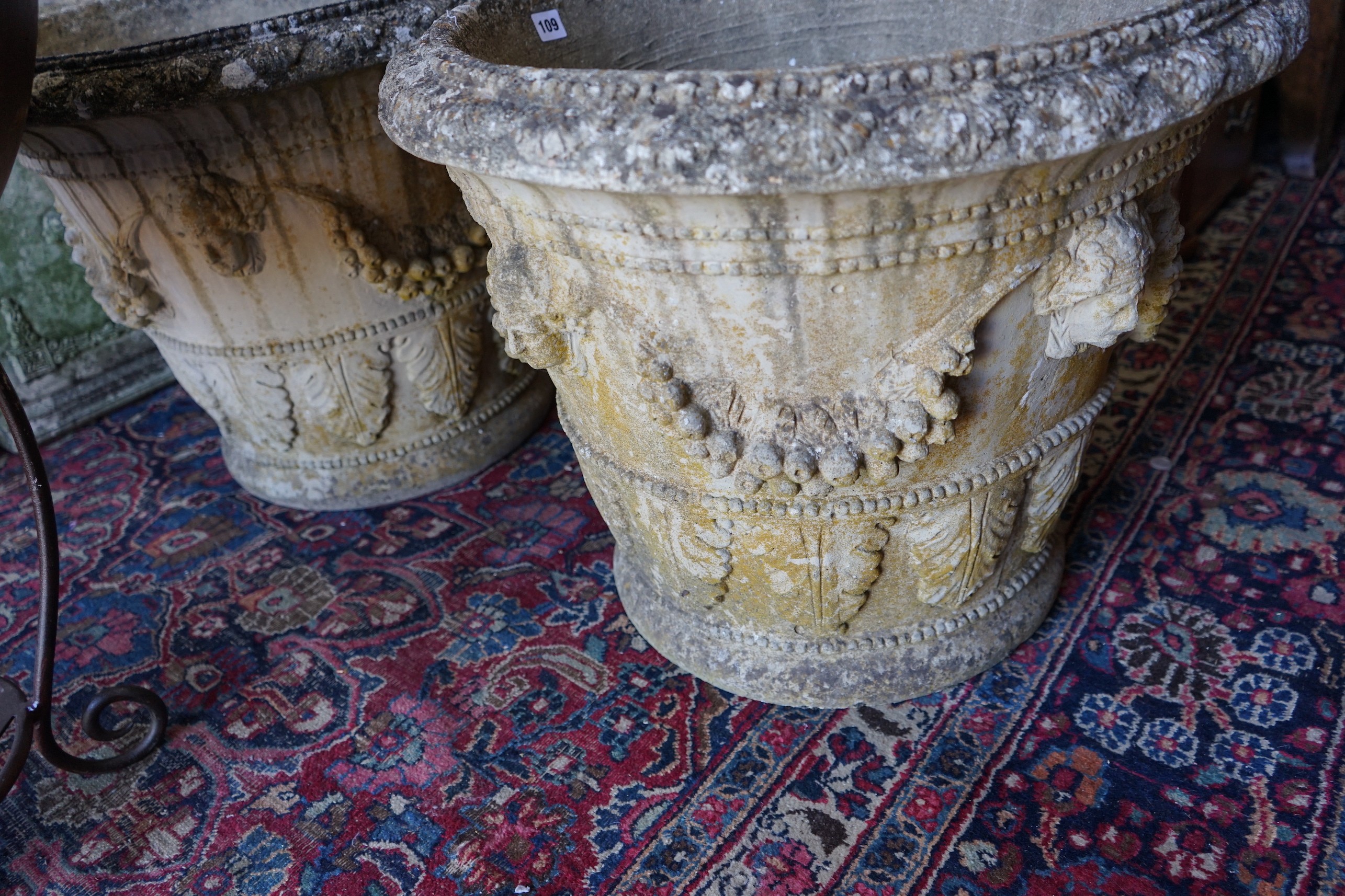 A pair of circular reconstituted stone garden planters with fruit swagged mask bodies, diameter 59cm, height 50cm